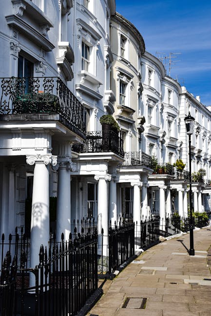 The exterior of a row of Victorian terraced houses in Ealing featuring brickwork with white decorative architectural details around arched windows and doorways, and black wrought iron railings along t